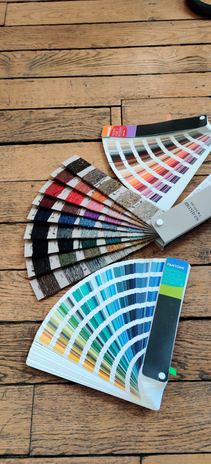 Nuanciers Pantone et cartes de fils ouverts en éventail pour valider les coloris d'une tenue d'entreprise